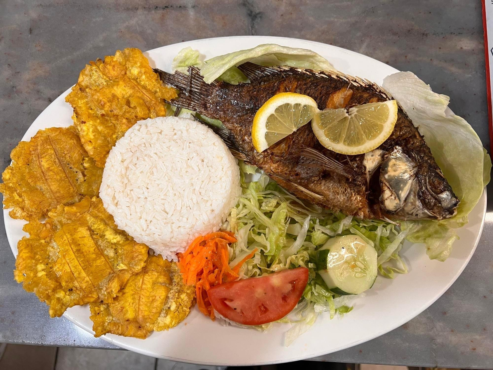 Whole fried mojarra fish with rice, tostones, and salad
